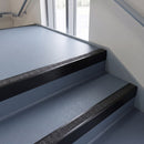 Square edge aluminium stair nosing with a dark charcoal Mor Grip insert in satin black finish fitted on a public building stair finished in blue-grey safety vinyl