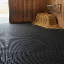 Horse stable loose box floor fully covered in black interlocking rubber matting with hay rack and straw bedding