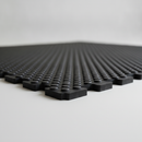Black interlocking rubber stable mat on studio background showing bubble-top texture and jigsaw edge