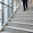 Brushed stainless steel stair nosing with black R11 anti-slip tread fitted to grey tiled steps in an office stair core