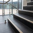 Stainless steel tile-in stair nosing with HB Light Beige RAL 1019 ribbed insert on dark charcoal tiled stairs