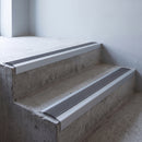 Silver anodised 46x30mm stair nosing with grey anti-slip rubber insert fitted to bare concrete stairs