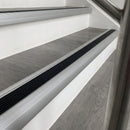 Aluminium stair nosing with black rubber insert fitted along grey wood-effect LVT treads in an office stairwell