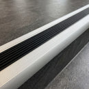 Close-up of the 25mm black grooved rubber insert and ribbed anodised silver channel on a fitted stair nosing