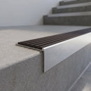 Slimline 59x30mm square back aluminium stair nosing with a dark peat brown ribbed PVC insert, on a satin aluminium bar, fitted along the front edge of a concrete step
