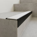Slimline 59x30mm square back aluminium stair nosing with a white ribbed PVC insert, on a black anodised bar, fitted along the front edge of a concrete step
