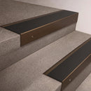 Bronze finish 66x55mm raked back aluminium stair nosing with a Black Smooth Textured insert, fitted to interior steps