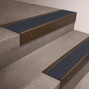 Bronze finish 66x55mm raked back aluminium stair nosing with a Granite Castellated insert, fitted to interior steps