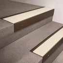 Bronze finish 66x55mm raked back aluminium stair nosing with a Ivory Castellated insert, fitted to interior steps
