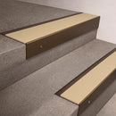 Bronze finish 66x55mm raked back aluminium stair nosing with a Porth Stone Smooth Textured insert, fitted to interior steps