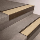 Bronze finish 66x55mm raked back aluminium stair nosing with a Porth Stone Smooth Textured insert, fitted to interior steps