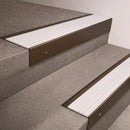 Bronze finish 66x55mm raked back aluminium stair nosing with a White Castellated insert, fitted to interior steps