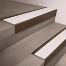 Bronze finish 66x55mm raked back aluminium stair nosing with a White Castellated insert, fitted to interior steps