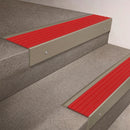 Light Bronze finish on a 66x55mm raked back aluminium stair nosing with a Poppy red insert, fitted indoors