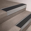 Mill Aluminium finish 66x55mm raked back aluminium stair nosing with a Black Smooth Textured insert, fitted to interior steps