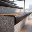 Solid brass bullnose stair nosing in Antique Bronze finish with Antique Brass matching solid brass infill fitted to a stair tread in a commercial stairwell
