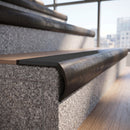 Solid brass bullnose stair nosing in Antique Bronze finish with Black Smooth Textured anti-slip infill fitted to a stair tread in a commercial stairwell