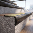 Solid brass bullnose stair nosing in Antique Bronze finish with Ivory Castellated anti-slip infill fitted to a stair tread in a commercial stairwell