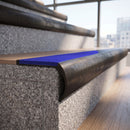 Solid brass bullnose stair nosing in Antique Bronze finish with Mid Blue Castellated anti-slip infill fitted to a stair tread in a commercial stairwell