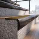 Solid brass bullnose stair nosing in Antique Bronze finish with Olive Castellated anti-slip infill fitted to a stair tread in a commercial stairwell