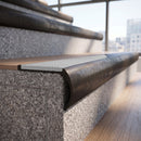 Solid brass bullnose stair nosing in Antique Bronze finish with Polar Grey Smooth Textured anti-slip infill fitted to a stair tread in a commercial stairwell