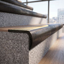 Solid brass bullnose stair nosing in Antique Bronze finish with Polished Brass matching solid brass infill fitted to a stair tread in a commercial stairwell