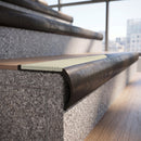 Solid brass bullnose stair nosing in Antique Bronze finish with Porth Stone Smooth Textured anti-slip infill fitted to a stair tread in a commercial stairwell