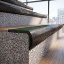 Solid brass bullnose stair nosing in Antique Bronze finish with Spruce Castellated anti-slip infill fitted to a stair tread in a commercial stairwell