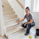 Female tiler pointing at aluminium stair nosing with charcoal grey anti-slip insert on cream porcelain tiled staircase UK