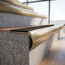 Solid brass bullnose stair nosing with matching Antique Bronze solid brass infill fitted to a stair tread in a commercial stairwell