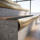 Solid brass bullnose stair nosing with Black Olympic Grip carborundum infill fitted to a stair tread in a commercial stairwell