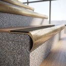Solid brass bullnose stair nosing with Granite Castellated anti-slip infill fitted to a stair tread in a commercial stairwell