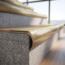 Solid brass bullnose stair nosing with Ivory Castellated anti-slip infill fitted to a stair tread in a commercial stairwell