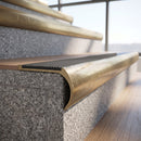 Solid brass bullnose stair nosing with Light Grey Castellated anti-slip infill fitted to a stair tread in a commercial stairwell