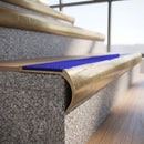 Solid brass bullnose stair nosing with Mid Blue Castellated anti-slip infill fitted to a stair tread in a commercial stairwell