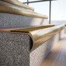 Solid brass bullnose stair nosing with Olive Castellated anti-slip infill fitted to a stair tread in a commercial stairwell