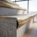 Solid brass bullnose stair nosing with Polar Grey Castellated anti-slip infill fitted to a stair tread in a commercial stairwell