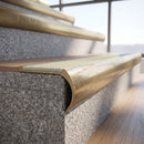 Solid brass bullnose stair nosing with Porth Stone Smooth Textured anti-slip infill fitted to a stair tread in a commercial stairwell