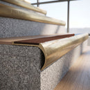Solid brass bullnose stair nosing with Rustic Castellated anti-slip infill fitted to a stair tread in a commercial stairwell