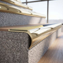 Solid brass bullnose stair nosing in Polished Brass finish with Ivory Castellated anti-slip infill fitted to a stair tread in a commercial stairwell