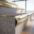 Solid brass bullnose stair nosing in Polished Brass finish with Light Grey Castellated anti-slip infill fitted to a stair tread in a commercial stairwell
