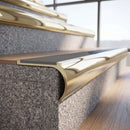 Solid brass bullnose stair nosing in Polished Brass finish with Light Grey Smooth Textured anti-slip infill fitted to a stair tread in a commercial stairwell