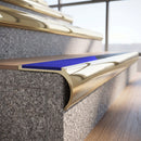 Solid brass bullnose stair nosing in Polished Brass finish with Mid Blue Castellated anti-slip infill fitted to a stair tread in a commercial stairwell