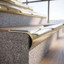 Solid brass bullnose stair nosing in Polished Brass finish with Polar Grey Castellated anti-slip infill fitted to a stair tread in a commercial stairwell