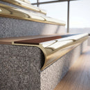 Solid brass bullnose stair nosing in Polished Brass finish with Rustic Castellated anti-slip infill fitted to a stair tread in a commercial stairwell