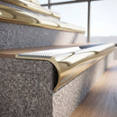 Solid brass bullnose stair nosing in Polished Brass finish with White Castellated anti-slip infill fitted to a stair tread in a commercial stairwell