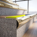 Solid brass bullnose stair nosing in Polished Brass finish with Yellow Castellated anti-slip infill fitted to a stair tread in a commercial stairwell