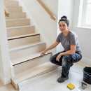 Female tiler pointing at aluminium stair nosing with rich brown anti-slip insert on cream porcelain tiled staircase UK
