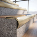 Solid brass bullnose stair nosing in Satin Brass finish with Antique Brass matching solid brass infill fitted to a stair tread in a commercial stairwell