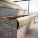 Solid brass bullnose stair nosing in Satin Brass finish with Claret Castellated anti-slip infill fitted to a stair tread in a commercial stairwell